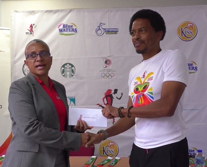 TTIM chairperson Diane Henderson presents a contribution towards the TTOC Gold Foundation, formally the TTOC Athlete Welfare and Preparation Fund, to Brian Lewis, immediate past president of the TTOC at a media briefing held to distribute special prizes for this year's event at the TTOC head office, Woodford Street, Port-of-Spain on Monday. (Image from guardian.co.tt)